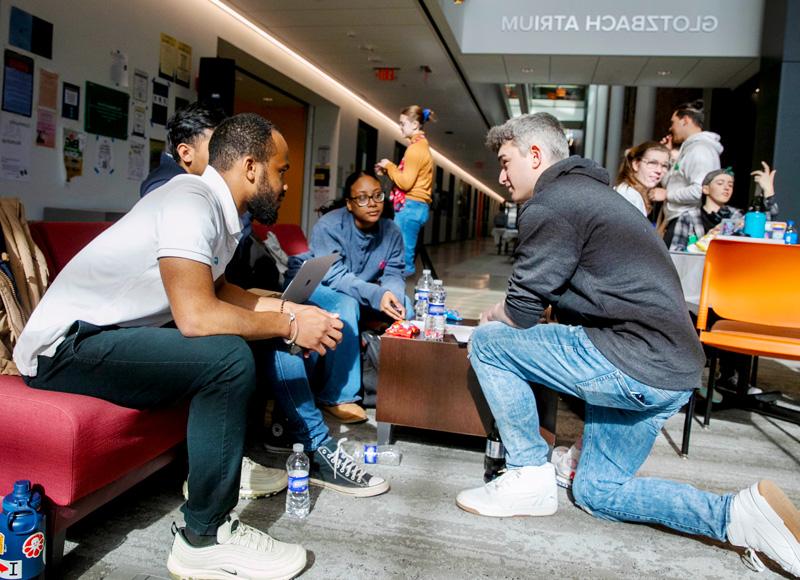 four college students gather around a couch to brainstorm 